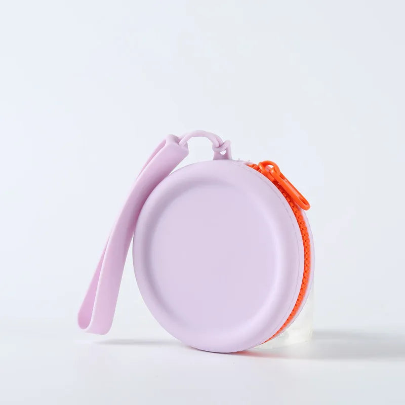Uma bolsa redonda lilás com zíper laranja e alça de pulso da mesma cor da bolsa.