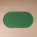 Tapete oval verde para alimentação de pets, com borda elevada, estendido sobre um piso de madeira.