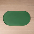 Tapete oval verde para alimentação de pets, com borda elevada, estendido sobre um piso de madeira.