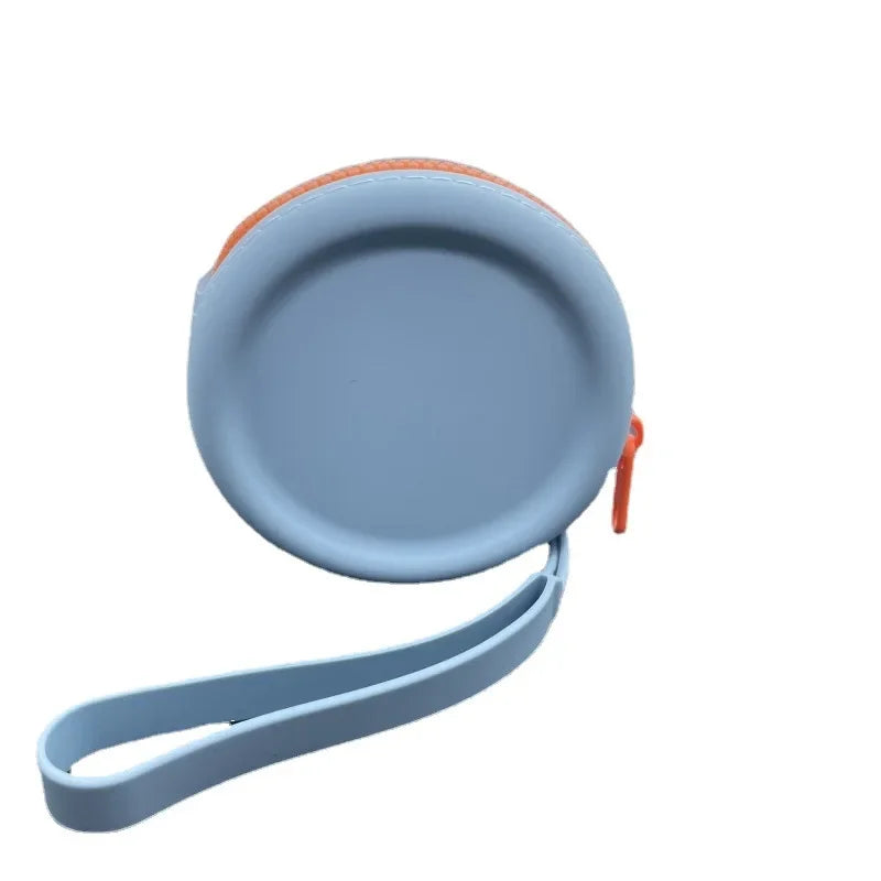 Uma bolsa redonda azul-clara para petiscos, fechada, com zíper laranja e alça de pulso da mesma cor da bolsa.