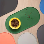 Um tapete verde com tigela amarela e ração espalhada, cercado por exemplos de outras cores. Tigela e alimento não incluídos.