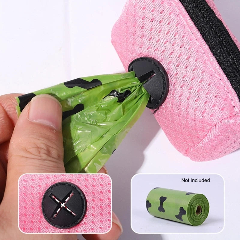 Uma mão puxando um saco verde pela abertura de um suporte rosa; a imagem do fornecedor indica que o rolo não está incluído.